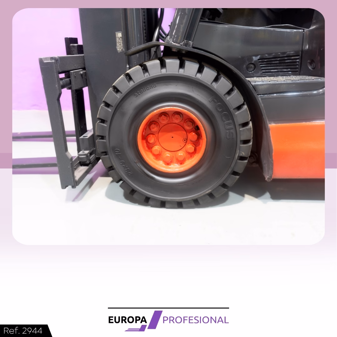 6 - EUROPA PROFESIONAL Close-up of a forklift wheel with a black tire and orange rim, pink/purple backdrop and lifting fork to the left.